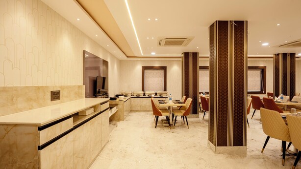 Una moderna hall d'albergo con una reception in marmo, una sala da pranzo con sedie e un'imponente colonna.