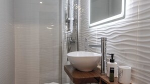 Une salle de bain moderne avec un grand lavabo blanc, un meuble-lavabo en bois, un miroir et un espace douche.