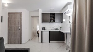 Une cuisine moderne équipée d’un lave-vaisselle intégré, d’un petit réfrigérateur et d’un plan de travail de couleur sombre.