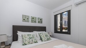 Une chambre d’hôtel avec un lit, des oreillers, une table de chevet, une lampe et une fenêtre donnant sur un paysage agréable.