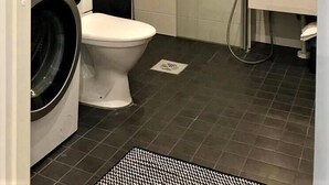 Ett litet badrum med tvättmaskin, toalett och en duschhörna.