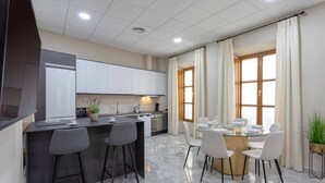 A modern kitchen with a central island, bar stools, and a dining area with a round table and chairs.