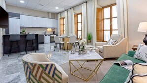 A modern living room with a green sofa, a coffee table, and a dining area with a table and chairs.