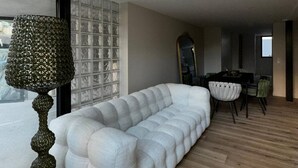 A modern living room with a white sofa, a decorative floor lamp, and a dining area with a table and chairs. - Nice Living Cannes Plage (Cannes)
