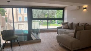 A modern living room with a glass partition, a sofa, and a chair. - Nice Living Cannes Plage (Cannes)