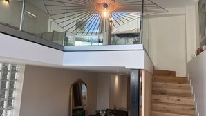A modern interior with a dining area, staircase, and a unique ceiling light fixture. - Nice Living Cannes Plage (Cannes)