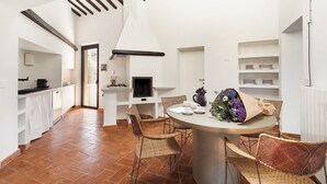 Une cuisine moderne avec des meubles blancs, un coin repas avec des chaises en osier et une table dressée pour deux personnes.