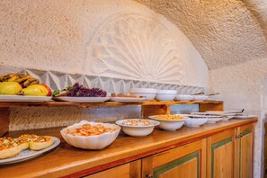 A buffet setup with various dishes and fruits on a wooden counter.