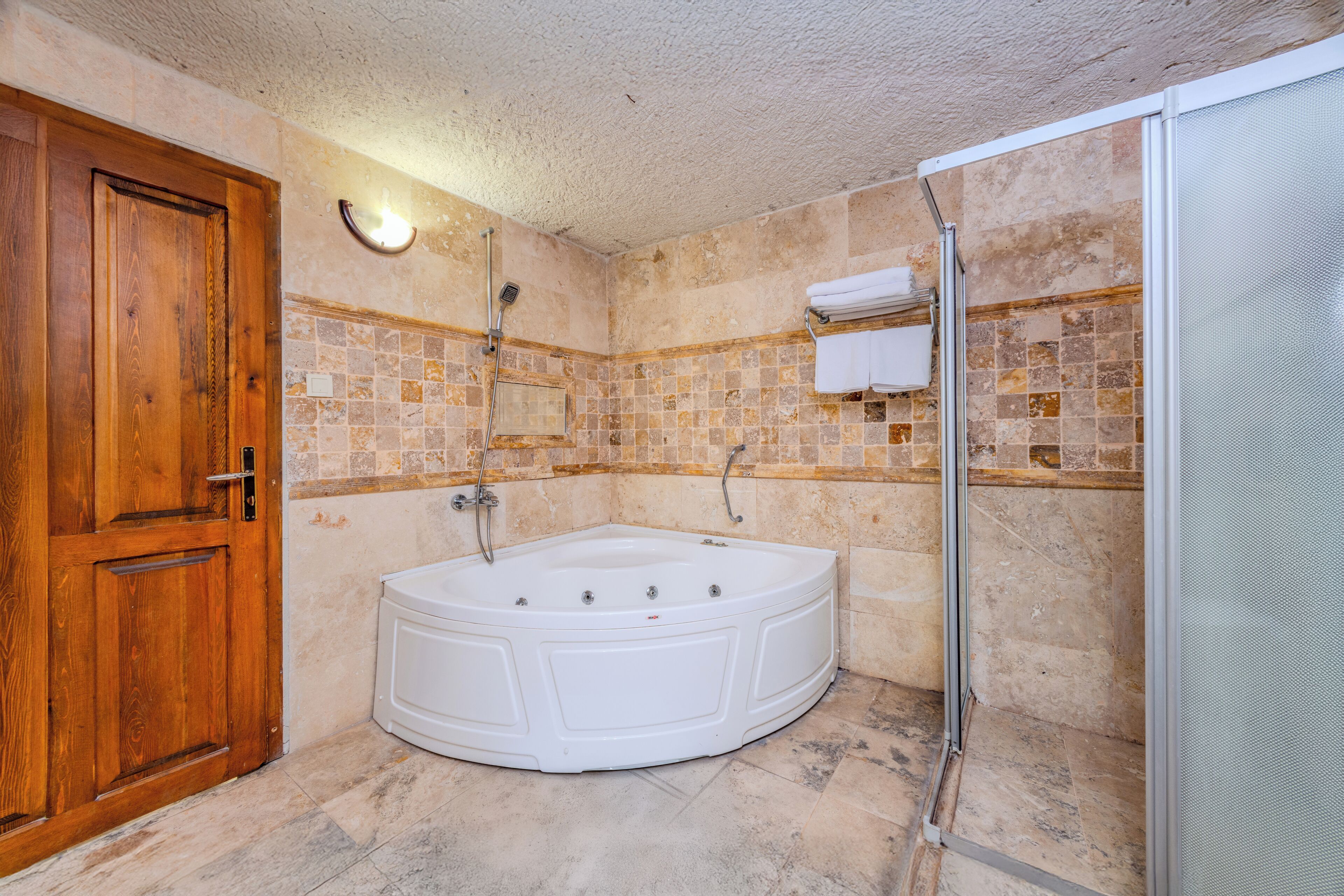 Ein Badezimmer mit Holztür, einer weißen Badewanne und einer Duschkabine.