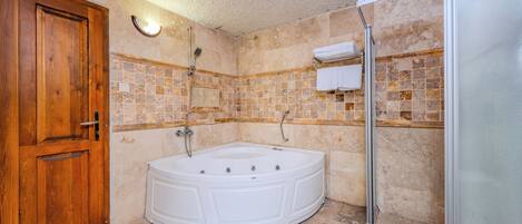 Une salle de bain avec une porte en bois, une baignoire blanche et un espace douche.