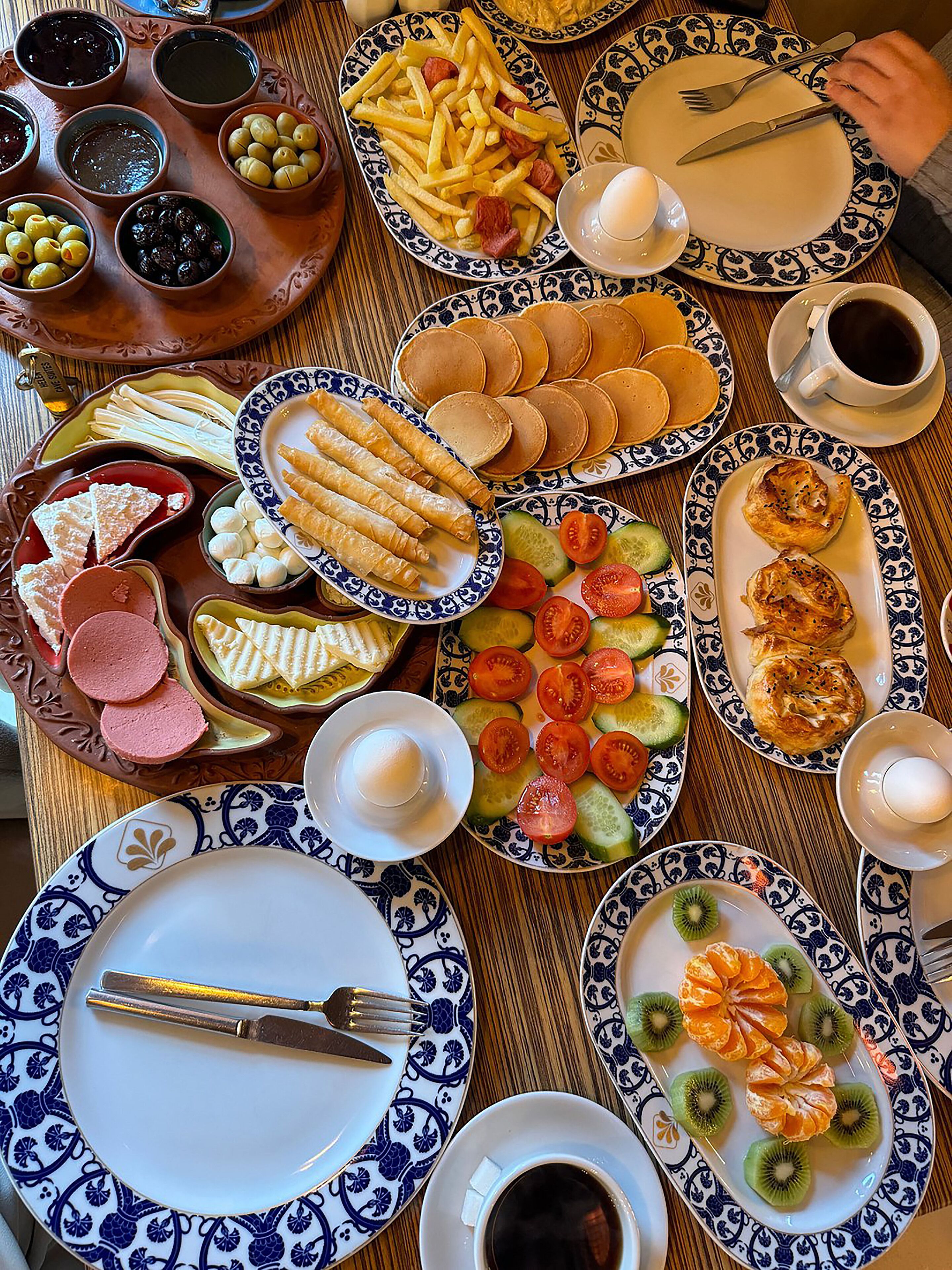 A table with various dishes including pancakes, croissants, and fruit.