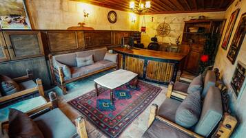 A cozy, rustic interior with a sofa, chairs, a coffee table, a bar area, and a decorative rug.