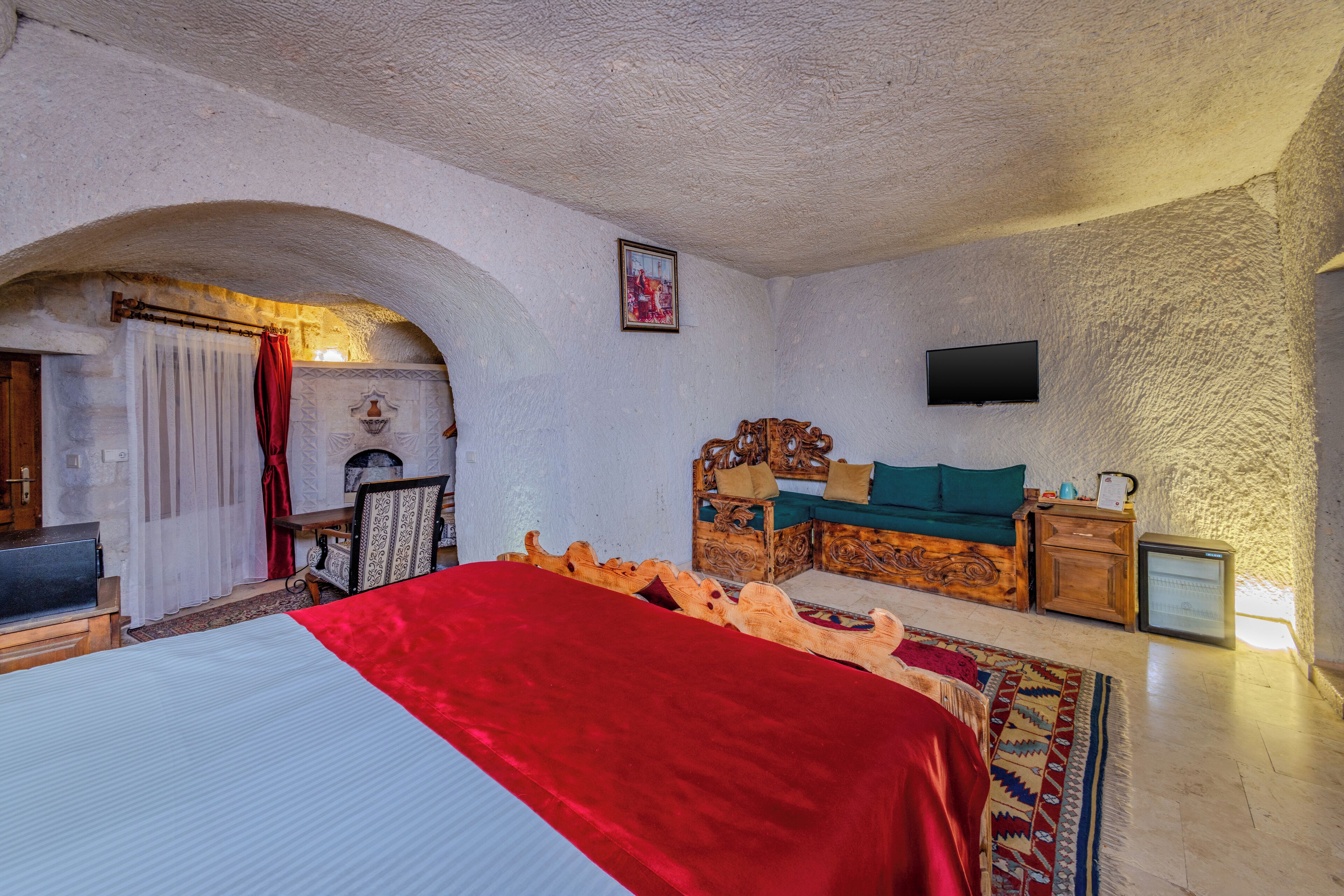A bedroom with a bed, a wooden headboard, a television, and a small table.