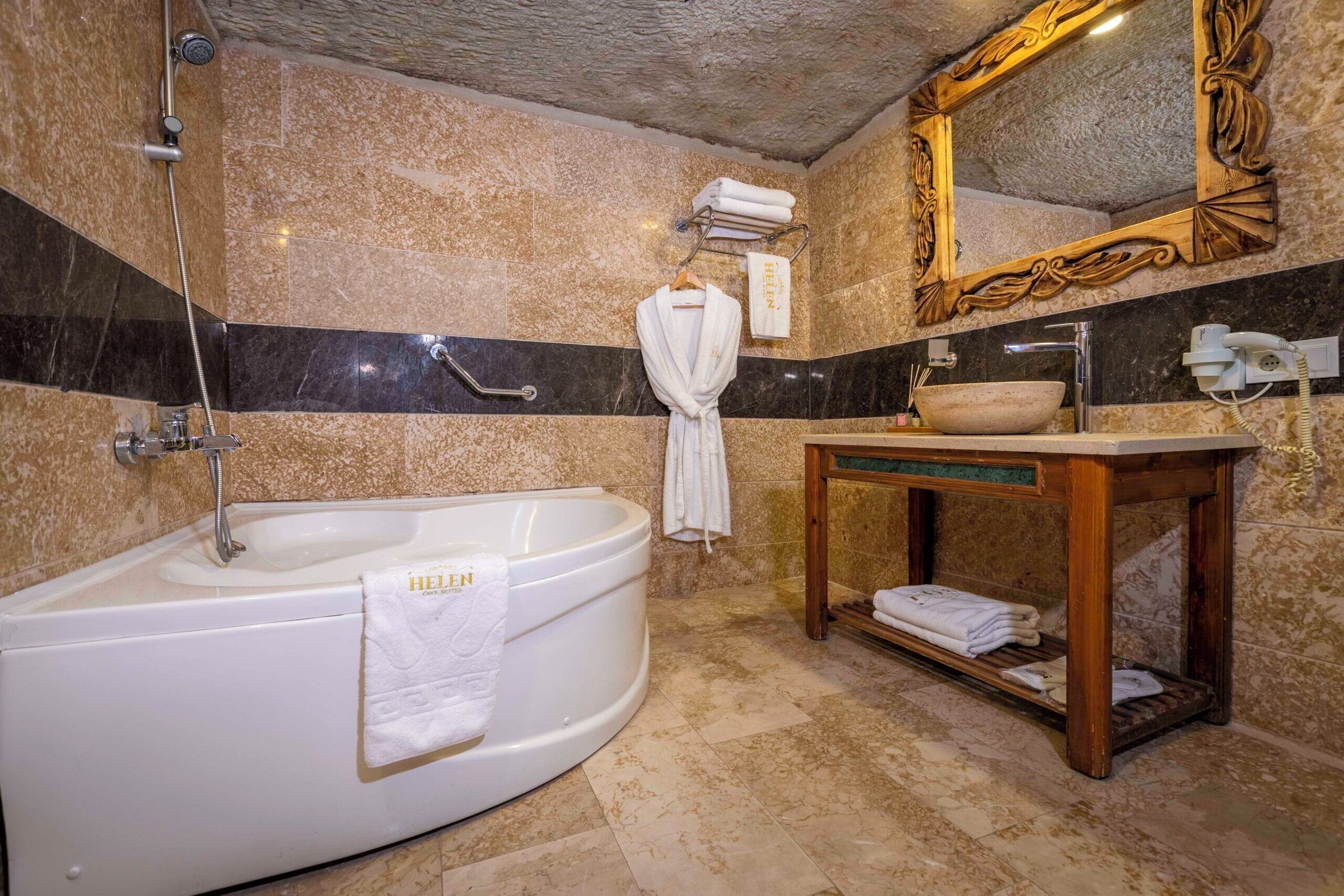 Un baño con una bañera independiente, un tocador con lavamanos, un espejo y un perchero para toallas.