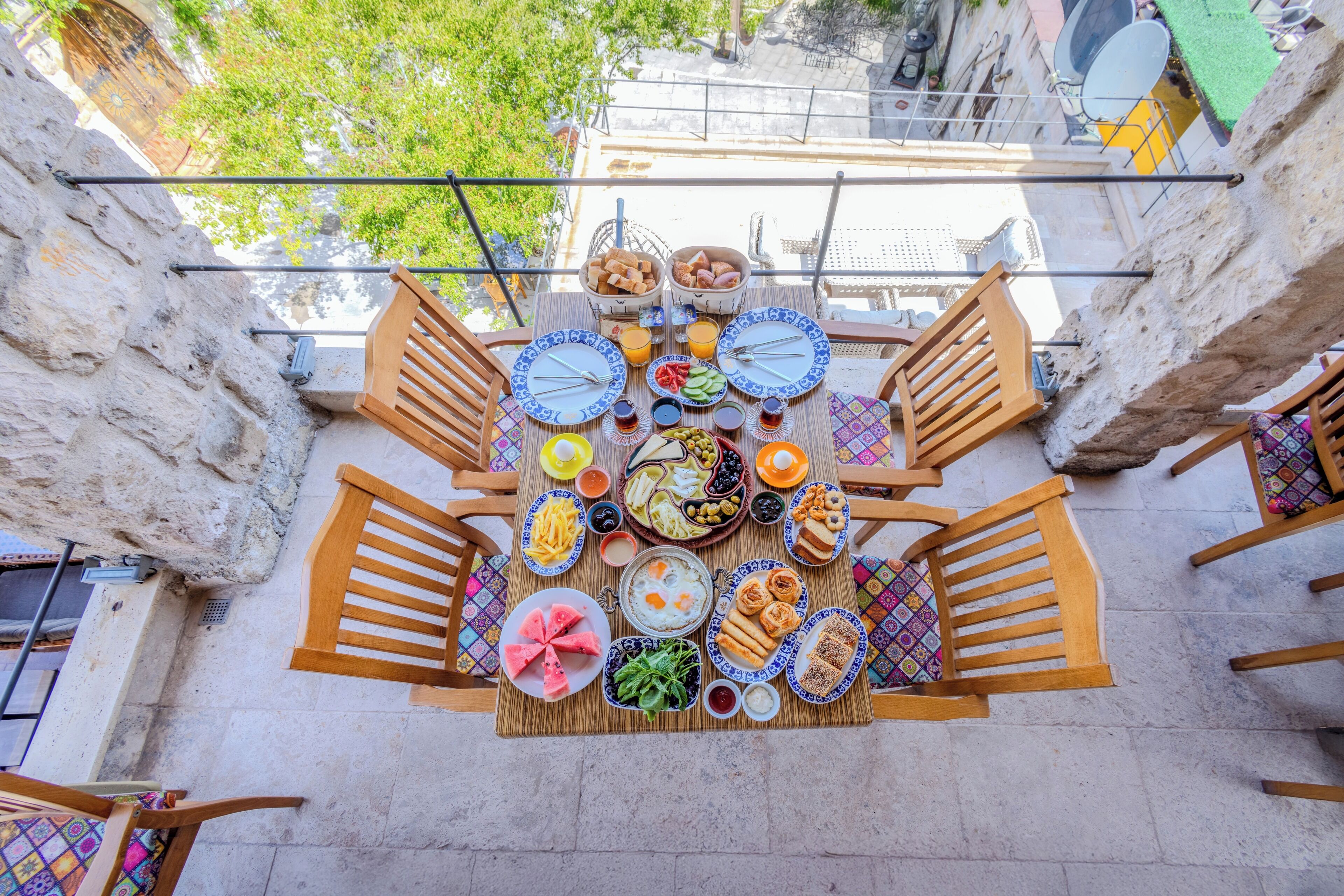 A rooftop terrace with a table set for a meal, surrounded by stone walls and wooden railings.