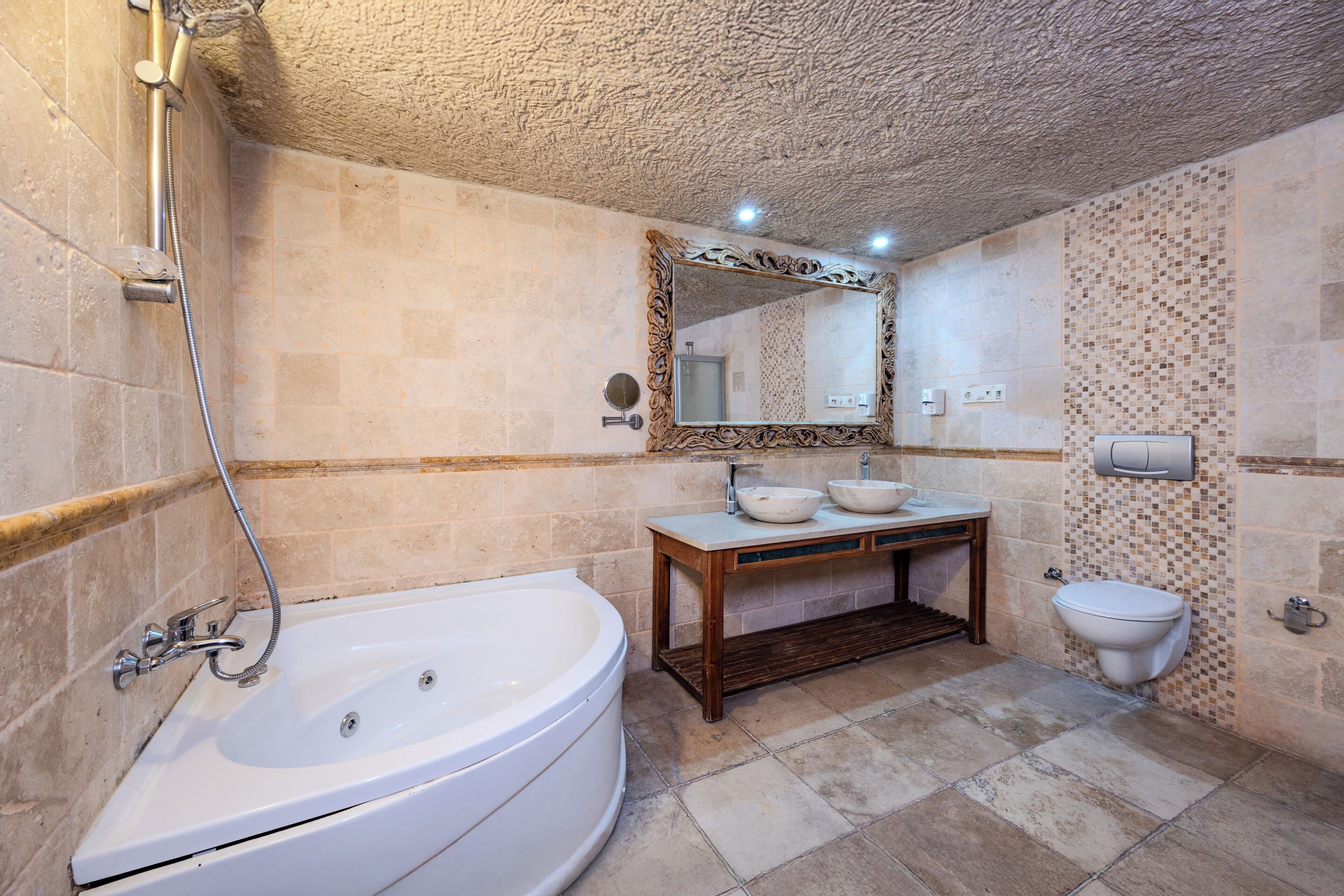 Un baño con una bañera independiente, un tocador de madera con lavamanos y un inodoro.