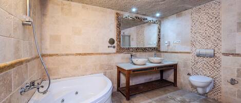 Un baño con una bañera independiente, un tocador de madera con lavamanos y un inodoro.