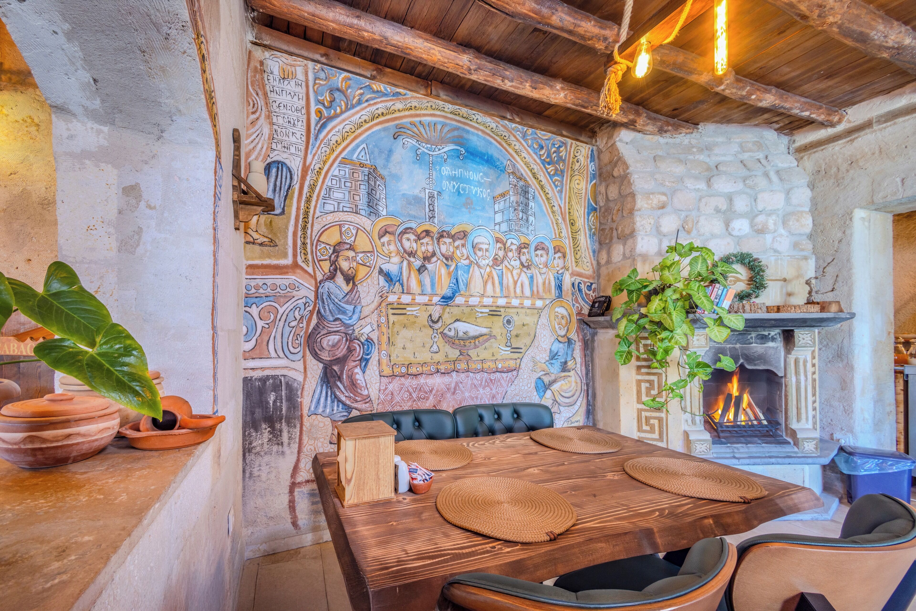 A rustic dining area with a mosaic wall, a fireplace, and a wooden table with woven placemats.