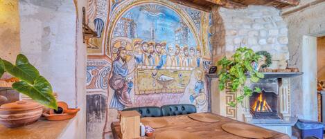 A rustic dining area with a mosaic wall, a fireplace, and a wooden table with woven placemats.