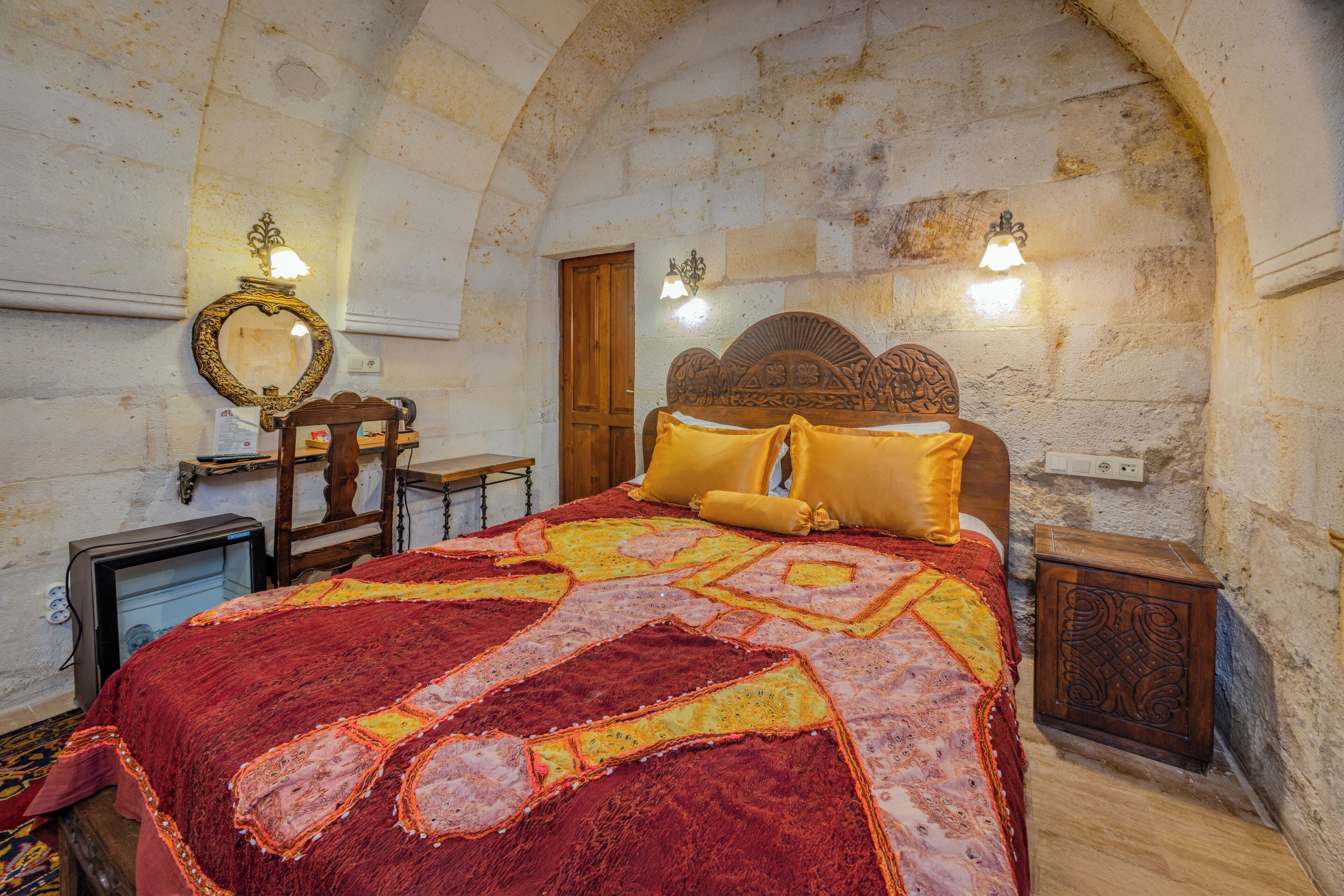 A bedroom with a large bed, a wooden headboard, a mirror, and two bedside tables.