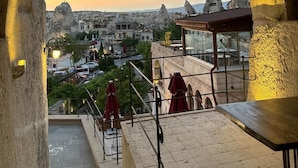 Vista a través de un arco sobre una ciudad con edificios históricos y una puesta de sol.