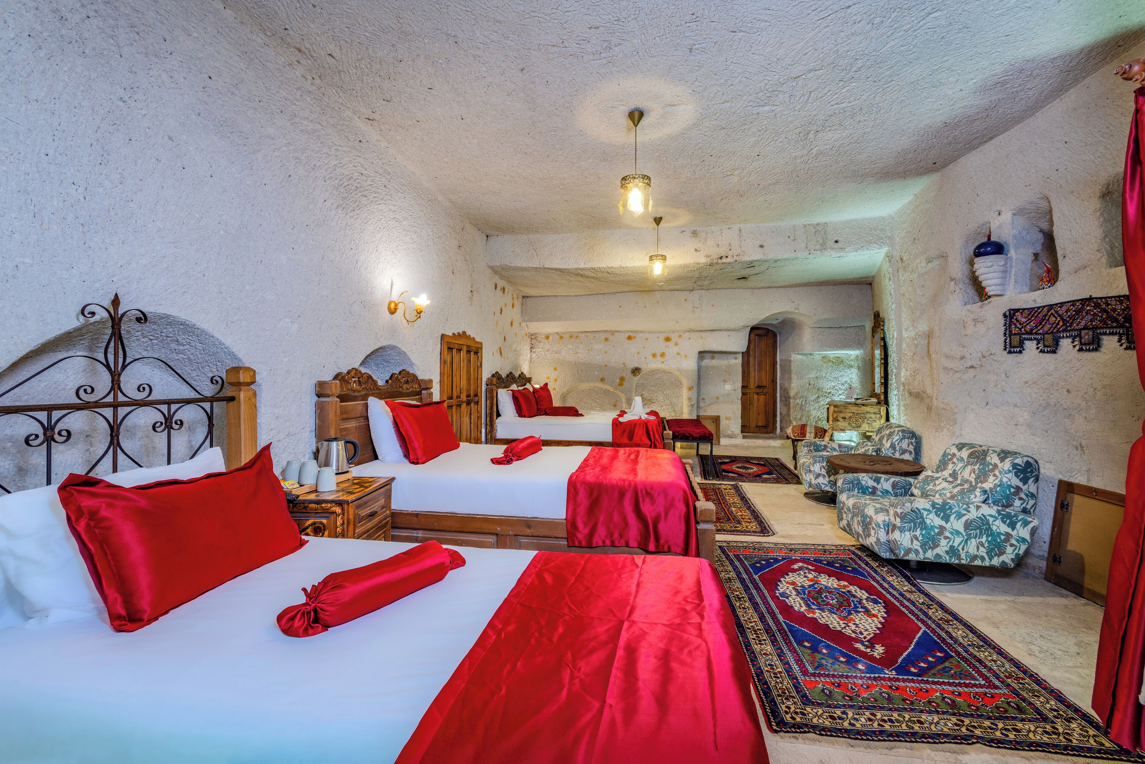 A traditional room with two beds, a sofa, and a patterned rug.