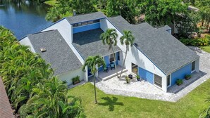 Una casa moderna de dos pisos con un amplio balcón y vista a un lago.