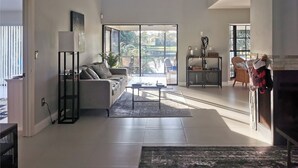 Amplia sala de estar con un sofá, una mesa de centro y vistas al exterior a través de ventanas grandes.