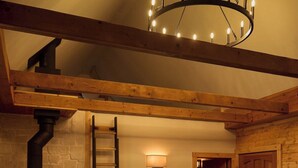 A cozy living room with a fireplace, wooden beams, a sofa, and a chandelier. - Aspen Hideway · Mountain Modern log Cabin Deck + Hot Tub (Florissant)