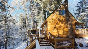 A wooden cabin with a wooden deck and stairs leading up to the entrance. - Aspen Hideway · Mountain Modern log Cabin Deck + Hot Tub (Florissant)