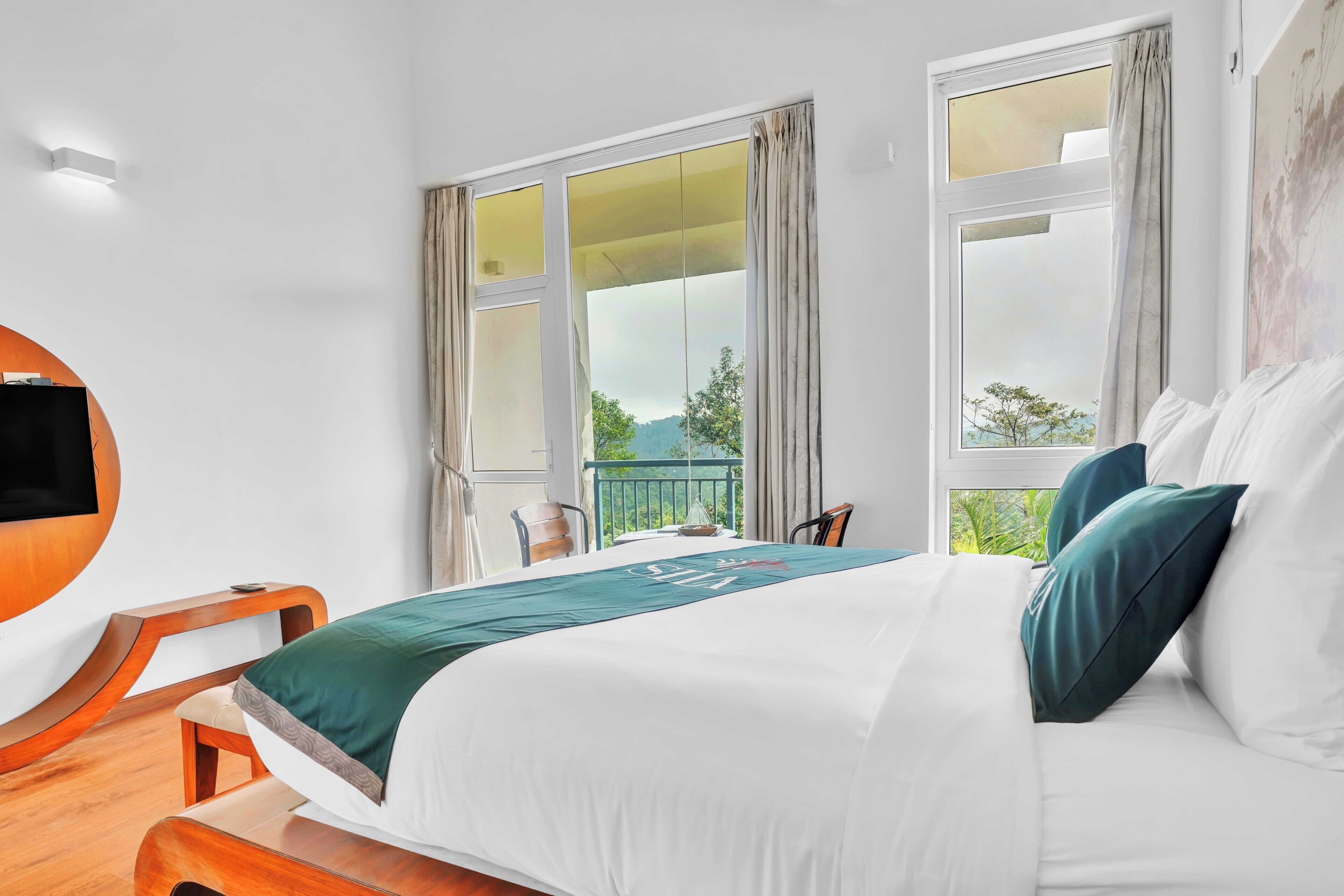 A hotel room with a bed, a TV, and a balcony with curtains.