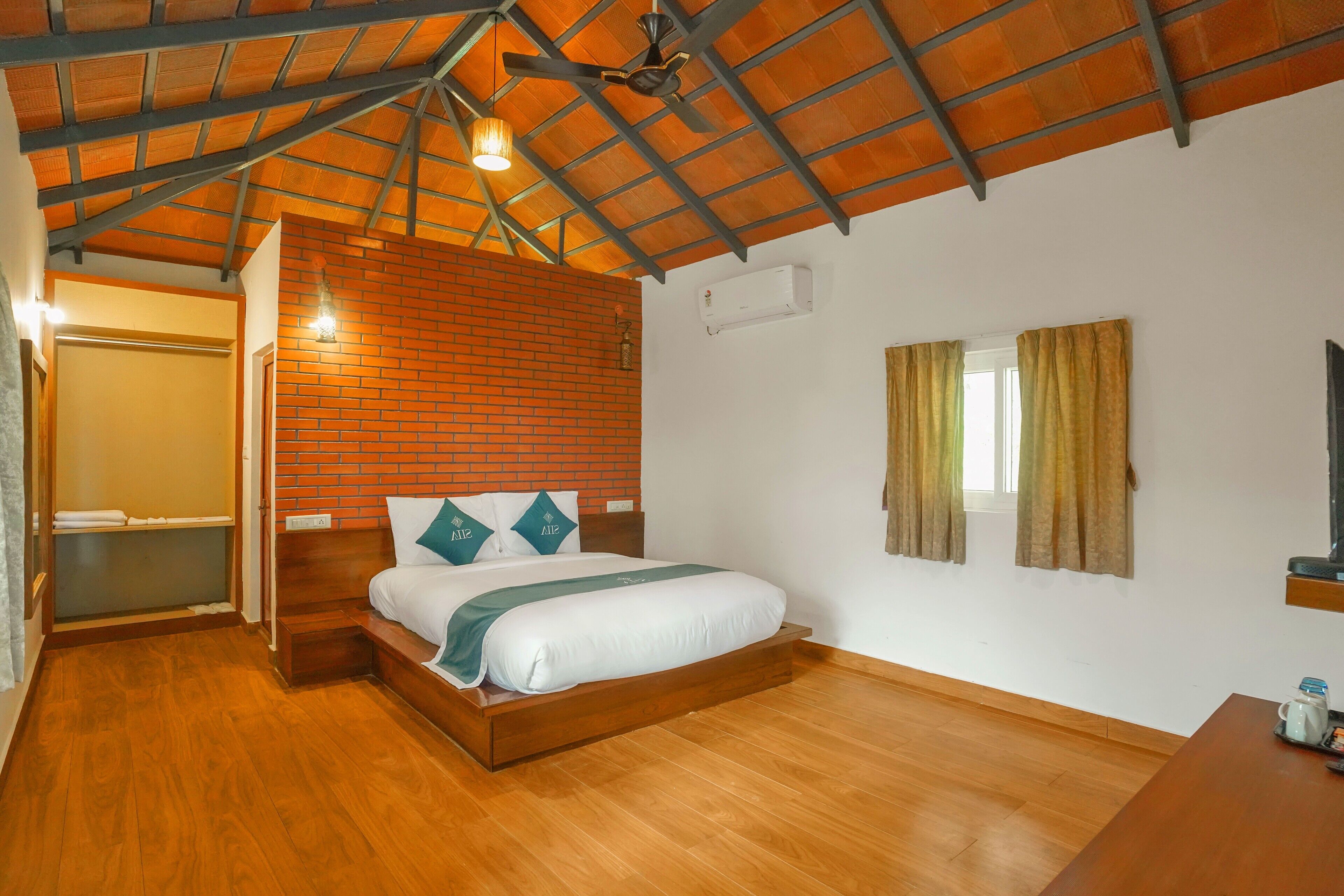 A bedroom with a wooden bed, a brick accent wall, a ceiling fan, and a window with curtains.