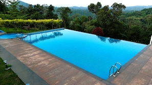 Relax by the serene pool surrounded by lush greenery and breathtaking mountain views.