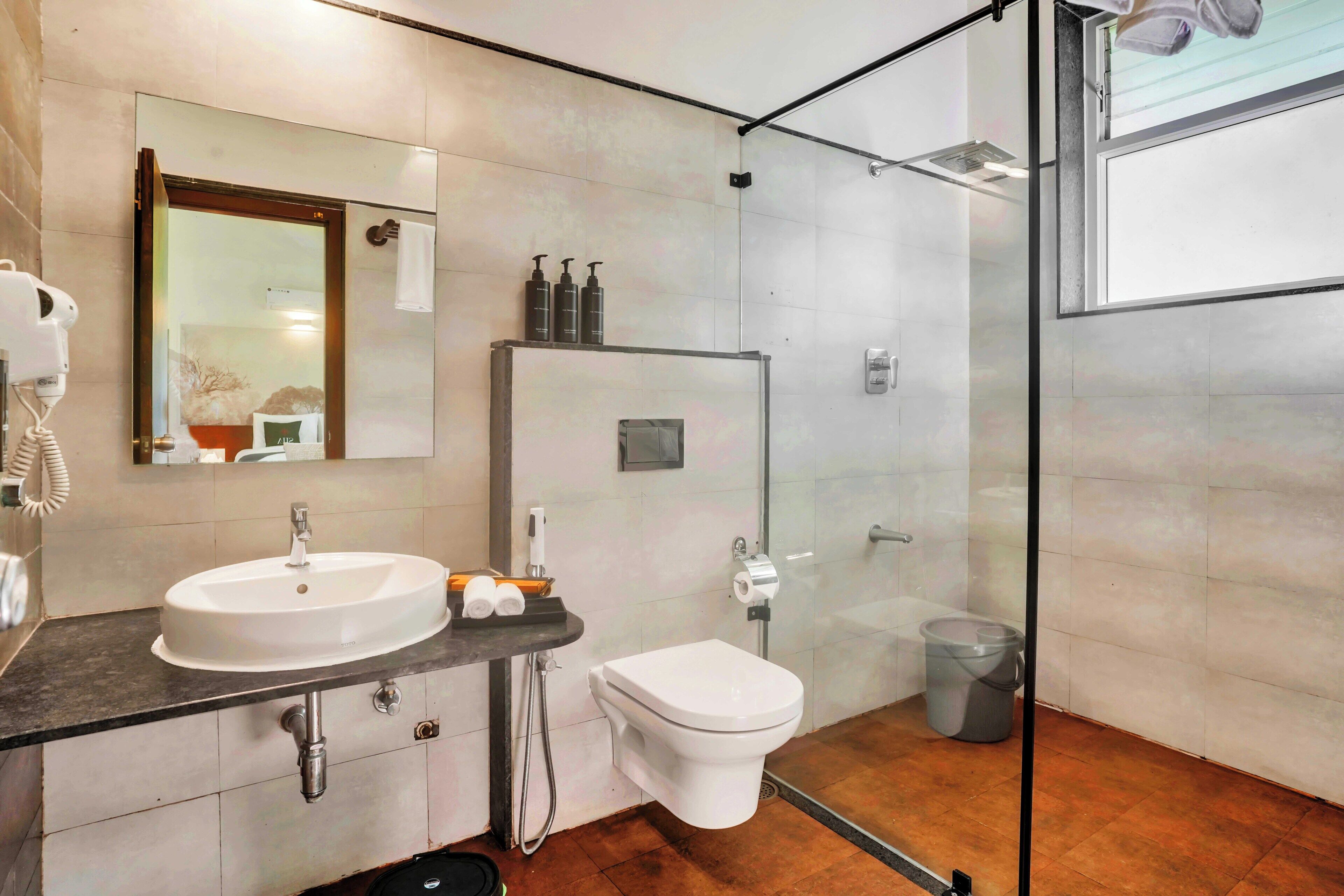 A modern bathroom with a glass shower enclosure, a white sink, and a toilet.