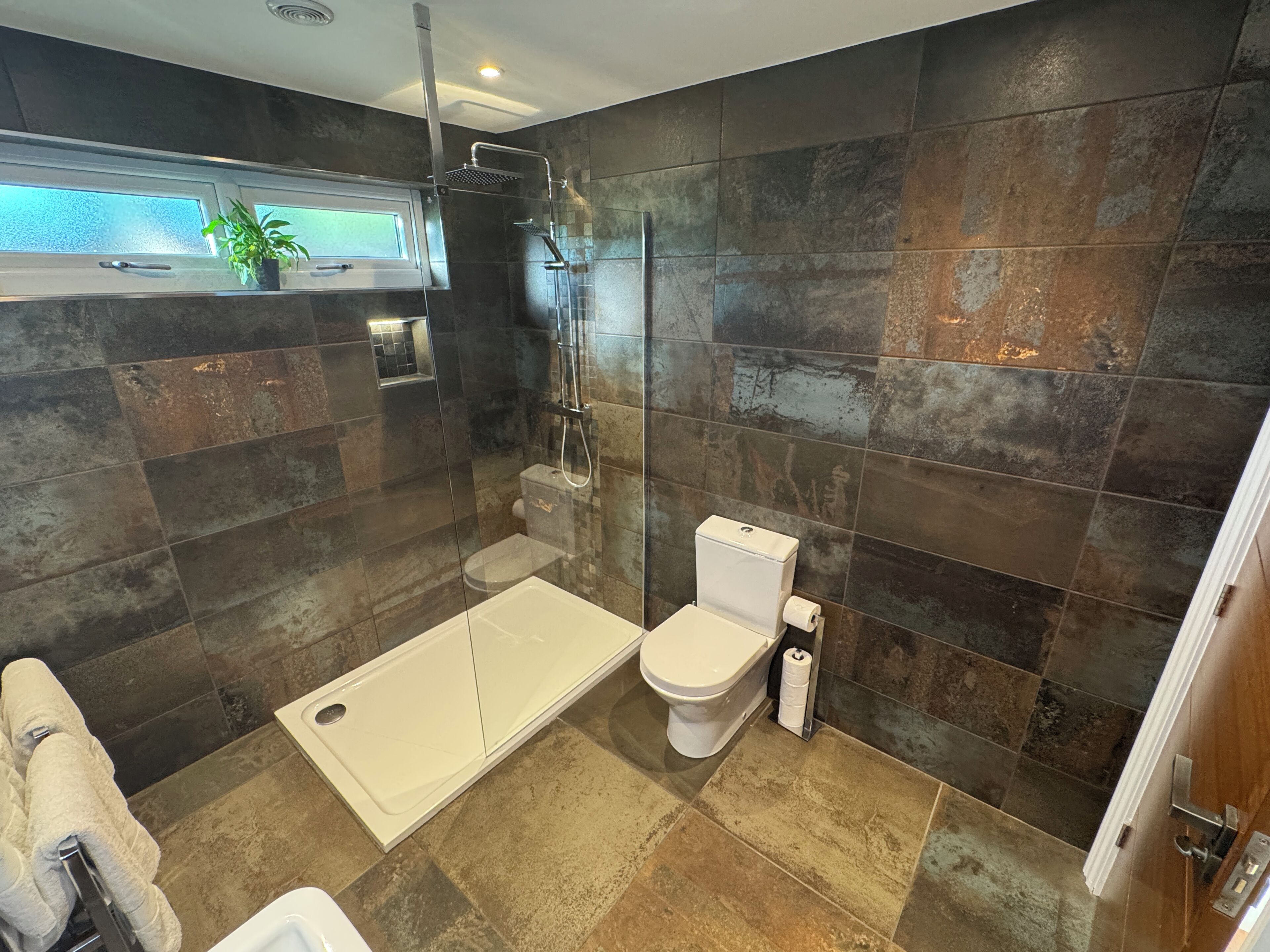 A modern bathroom with a glass-enclosed shower, a toilet, and a bathtub.
