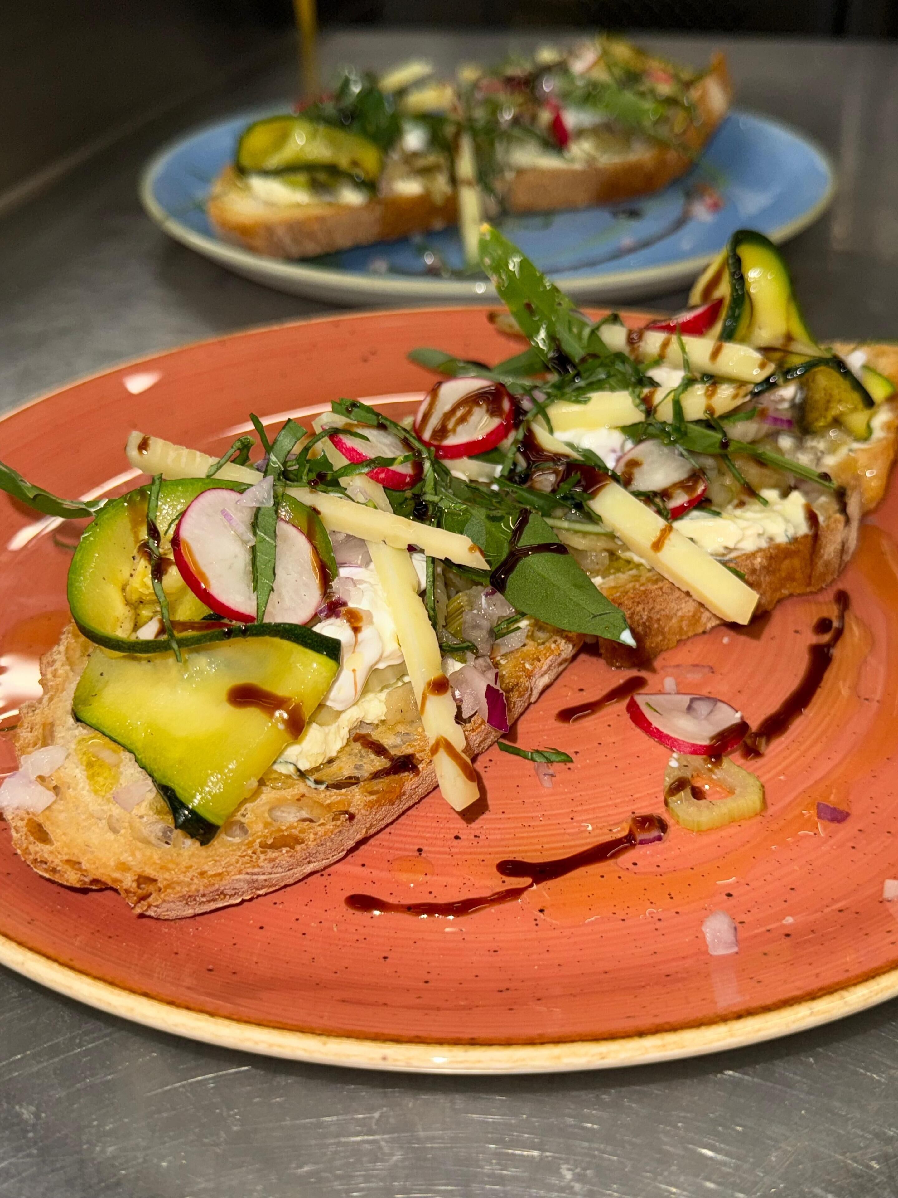 Un plat de brusquetes cobertes de verdures i salsa.
