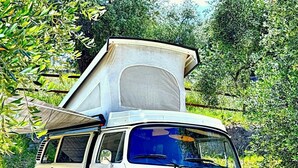Una furgoneta Volkswagen verde estacionada en una carretera con una gran carpa blanca en el techo.