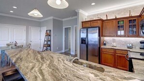 A kitchen with a large island, wooden cabinets, and a stainless steel refrigerator. - Beachgate Condo Suites And Hotel 341+342 4 Bedroom Condo (Port Aransas)