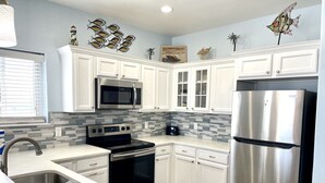 A modern kitchen with white cabinets, stainless steel appliances, and a tiled backsplash. - Beachgate Condo Suites And Hotel 331+332 4 Bedroom Condo (Port Aransas)