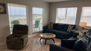 A living room with a sectional sofa, a single chair, and a coffee table. - Beachgate Condo Suites And Hotel 237+238+239 3 Bedroom Condo (Port Aransas)