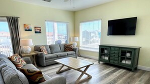 A living room with a grey sofa, a wooden coffee table, and a green cabinet. - Beachgate Condo Suites And Hotel 322 2 Bedroom Condo (Port Aransas)
