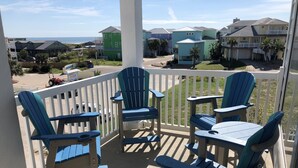 A balcony with blue Adirondack chairs and a view of a residential area with houses and a beach. - Beachgate Condo Suites And Hotel 322 2 Bedroom Condo (Port Aransas)