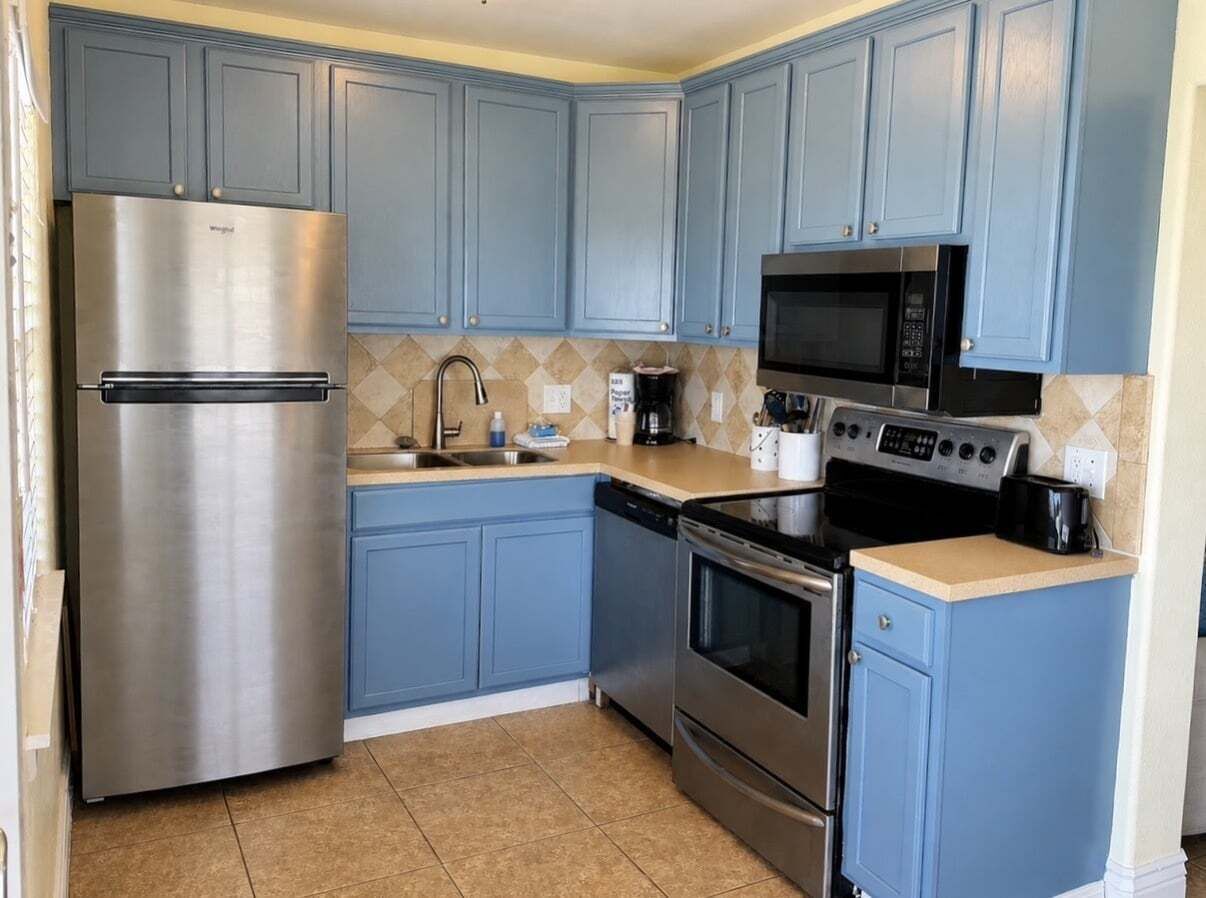 A kitchen with blue cabinets, stainless steel appliances, a microwave, and a stove.