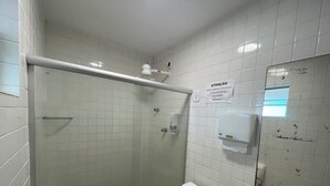 A bathroom with white tiled walls, a glass shower enclosure, a toilet, and a hand dryer. - Pousada Anadia (Anadia)