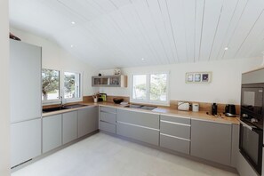 A modern kitchen with a large island, built-in appliances, and ample natural light. - Villa La Canopée - Ile d'Oléron - Chaucre - 8 pers - swimming pool (Saint-Georges-d'Oléron)