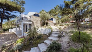 Une maison moderne avec une façade en pierre, un balcon et un escalier menant à un deuxième étage.