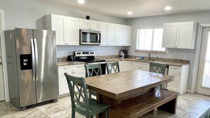 Una cocina moderna con armarios blancos, electrodomésticos de acero inoxidable y un gran comedor de madera.