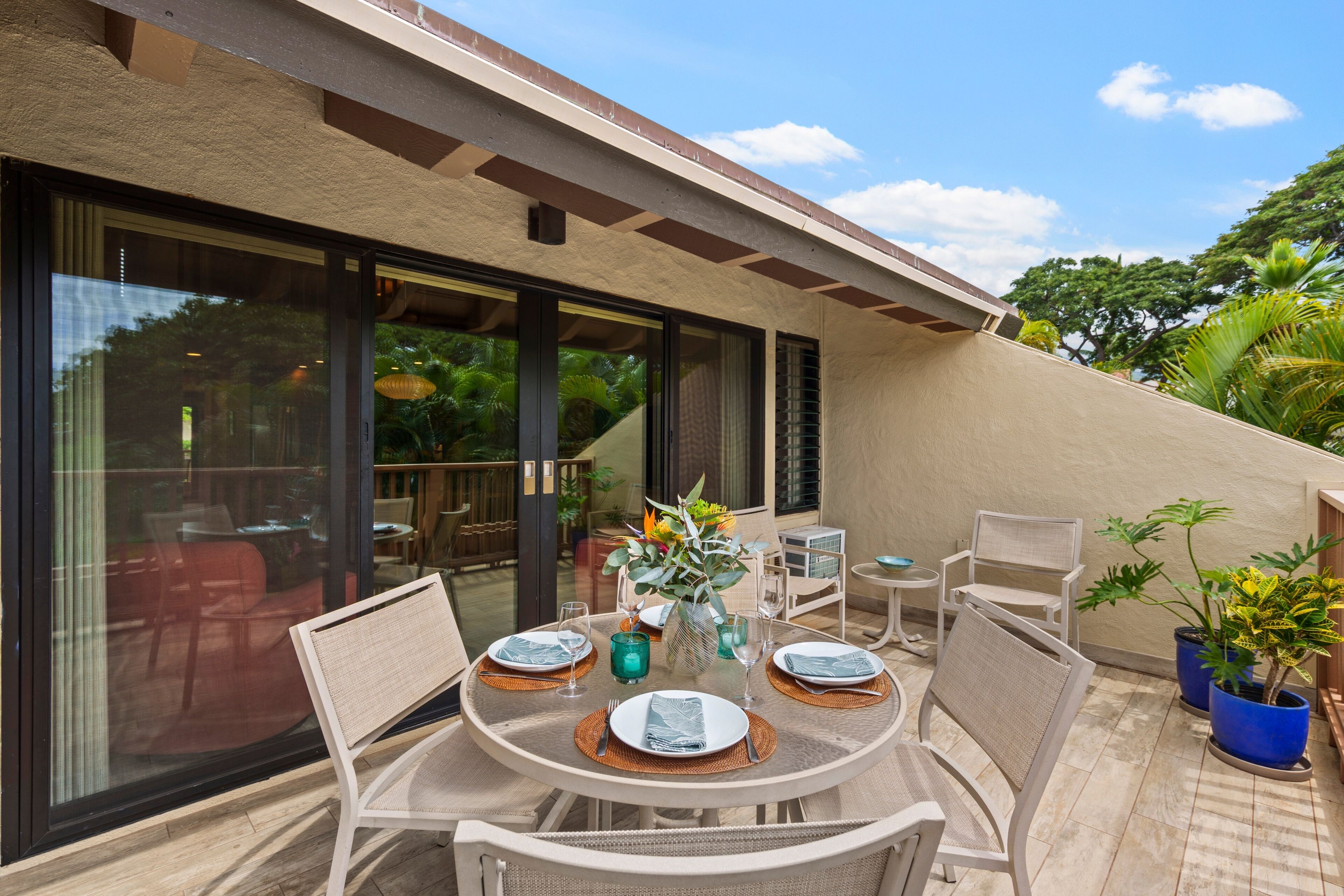 An outdoor dining area with a round table, chairs, and potted plants.