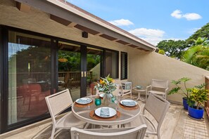 Un área de comedor al aire libre con una mesa redonda, sillas y plantas en macetas.