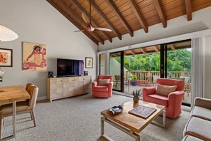 Un amplio salón con techo de madera, televisor, sofá y mesa de comedor.